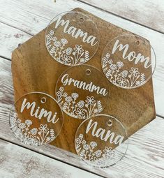 four personalized glass ornament hanging from a wooden board with flowers on it