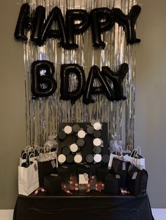 a black and white birthday party table with balloons, gift bags, and streamers