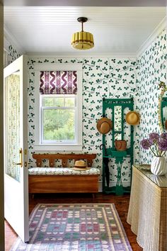 a living room with green and white wallpaper, rugs and furniture in front of a window