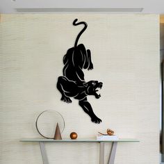 a wall mounted clock with a monkey on it's face next to a glass table