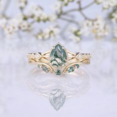 a close up of a ring on a white surface with flowers in the back ground