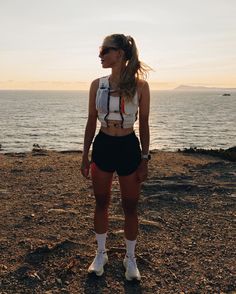 a woman standing on top of a beach next to the ocean