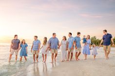 a family walking on the beach at sunset with their parents holding hands and children standing in front of them