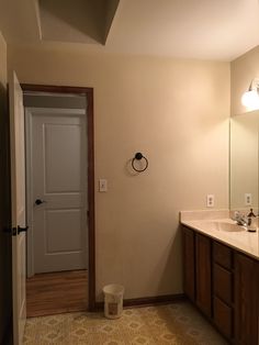 a bathroom with two sinks and a door leading to the other room in front of it