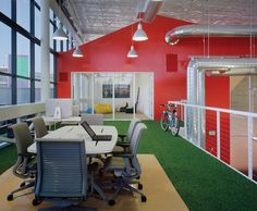 an office with green grass on the floor and red walls, along with lots of windows