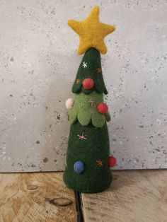 a small green christmas tree sitting on top of a wooden table