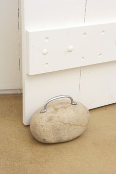 a rock sitting in front of a white door with a metal handle on it's side