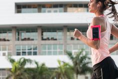 a woman running in front of a building with headphones on her ears and armbands