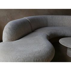 an oval shaped couch sitting on top of a table next to a round coffee table