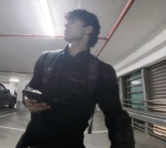 a young man is walking in an empty parking garage