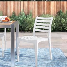 two white plastic chairs sitting on top of a blue rug next to a small table