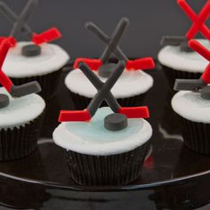 cupcakes with white frosting and black icing decorated like hockey goalies