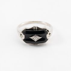 Hi. This is a pretty onyx ring with diamond accents in 10k white gold. The onyx stone measures approximately 7.5x14mm. At the center is a diamond accent. It is marked 10k on the inside of the ring. The ring finger size is 7.25. Sorry, we d not resize rings. The weight of the ring with stones is 3.4 grams. Thanks for looking. Formal Black Enamel Diamond Ring, Classic White Gold Rings With Black Enamel, Classic Formal Enamel Ring, Classic Diamond Enamel Ring For Formal Occasions, Classic Black Diamond Ring With Black Enamel, Classic White Gold Onyx Rings, Formal White Gold Enamel Ring With Diamond Accents, Classic Formal Enamel Diamond Ring, Black Enamel Diamond Ring For Anniversary