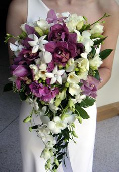 a bride holding a purple and white bouquet