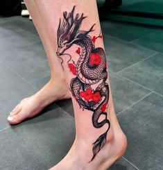 a woman's leg with a dragon tattoo on it and red flowers in the shape of hearts