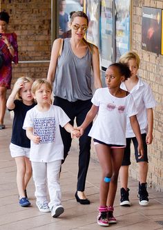 a group of children walking down a sidewalk holding hands