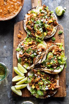 three tacos with shredded meat, avocado and cilantro on top