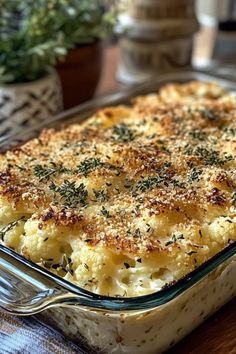 a casserole dish with cheese and herbs in it sitting on a wooden table