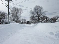 a person riding skis down a snow covered street next to power lines and telephone poles