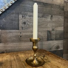 a white candle sitting on top of a wooden table next to a metal pipe holder