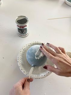 a person is using a spoon to dip something into a bowl with paint on it