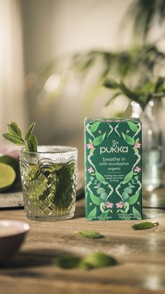 a box of pukka tea next to a glass filled with water and green leaves