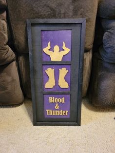 a purple and yellow poster with the words blood & thunder on it in front of a couch