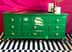 a green dresser sitting on top of a black and white checkered floor