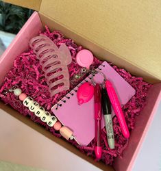 an open pink box with various items in it, including pens, scissors and other things