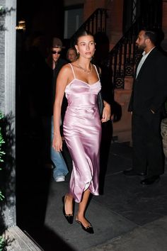 a woman in a pink dress is walking down the street