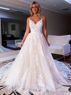 a woman wearing a white wedding dress standing in front of a mirror and looking at the camera