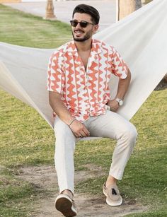 a man sitting in a hammock with his feet up on the ground and wearing sunglasses