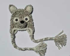 a knitted animal hat with tassels on the ends and eyes, made to look like a teddy bear