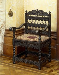 an ornate wooden chair sitting on top of a hard wood floor next to a wall