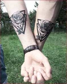 two people holding hands with tattoos on their arms