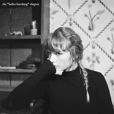 a black and white photo of a woman sitting at a table with her hand on her face