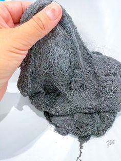 a hand is holding a gray cloth over a white sink