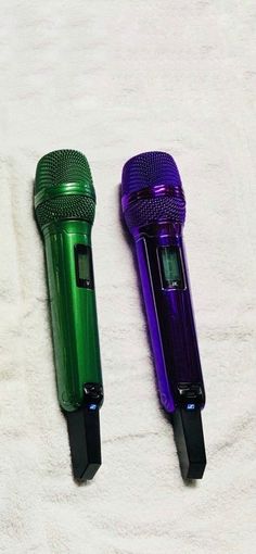 two green and purple microphones sitting on top of a white towel next to each other