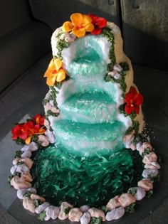 a three tiered cake decorated with flowers and shells on the bottom, sitting on top of a car seat