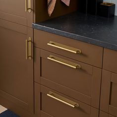 a kitchen with brown cabinets and black counter tops, gold pulls on the handles to match the cabinet doors