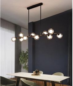 a dining room table with chairs and lights hanging from it's ceiling over it