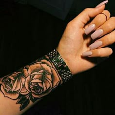 a woman's arm with a rose tattoo on it, and her hand holding the wrist