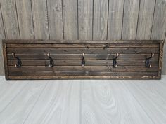 a coat rack made out of wood with hooks on the front and back sides, mounted to a wall