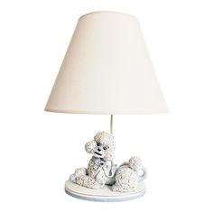 a white poodle lamp sitting on top of a table next to a light shade