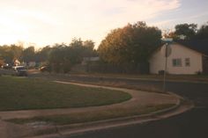 a street with cars parked on the side of it and houses in the back ground