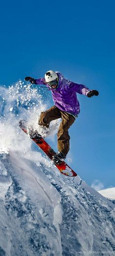 a snowboarder in purple jacket doing a trick on the side of a mountain