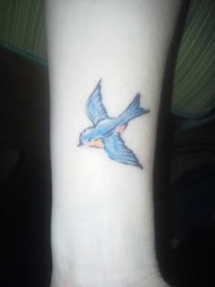 a small blue bird tattoo on the wrist