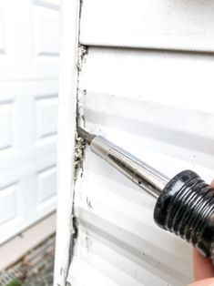 a person holding a screwdriver in front of a garage door that has been damaged