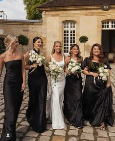 a group of women standing next to each other on a brick floored walkway with flowers in their hands