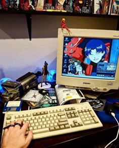 a person using a computer on a desk in front of a bunch of anime books